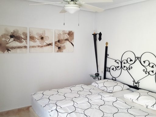 Slaapkamer met een bed, witte muren en decoratieve kunst aan de muur.